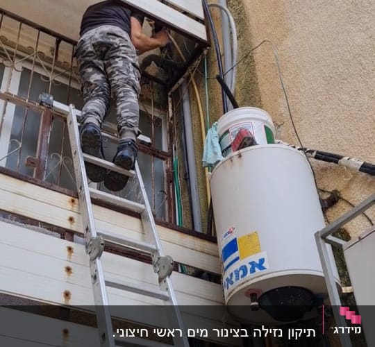 אדם על סולם מתקן צנרת ליד דוד שמש